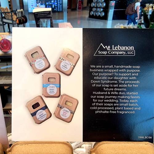 A display featuring handmade soap bars with labels, promoting Mt. Lebanon Soap Company and its mission to support a daughter with Down Syndrome.