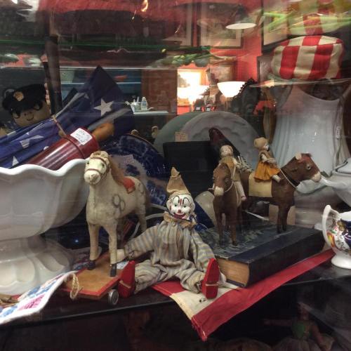 A display of vintage toys, including a clown doll, toy horses, and various collectibles in a glass case.