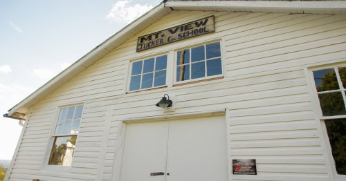 Exterior of a white wooden school building with a sign reading "Mt. View Tucker E. School" above the entrance.