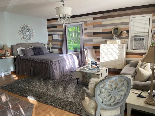 Cozy bedroom with a bed, stylish decor, a large window, and a mix of wood and light blue wall accents.