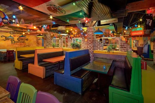 Colorful restaurant interior with vibrant booths, festive lights, and Mexican-themed decor.