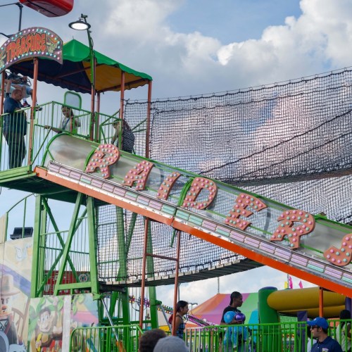 A colorful amusement park ride with the name "Raiders" and people enjoying the attractions in the background.