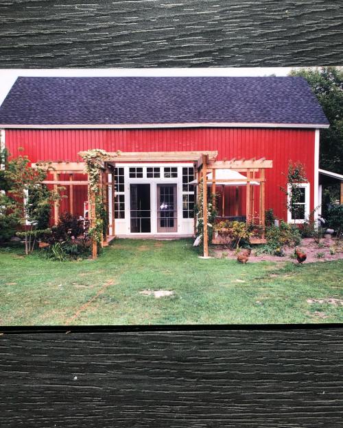 A red barn-style building with a wooden pergola and landscaped garden in front.