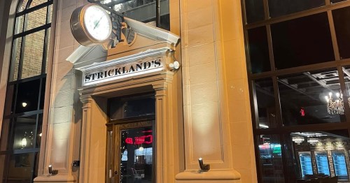 Exterior view of Strickland's restaurant at night, featuring a large clock and illuminated signage.