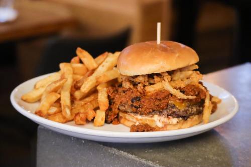 A hearty burger topped with chili and crispy onions, served with a side of golden French fries on a white plate.