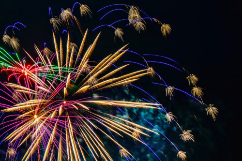 Colorful fireworks burst in the night sky, creating vibrant trails of light in various shapes and colors.