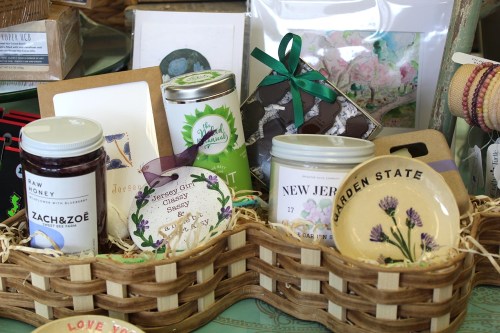 A woven basket filled with local products, including honey, sauces, and decorative items, showcasing New Jersey themes.