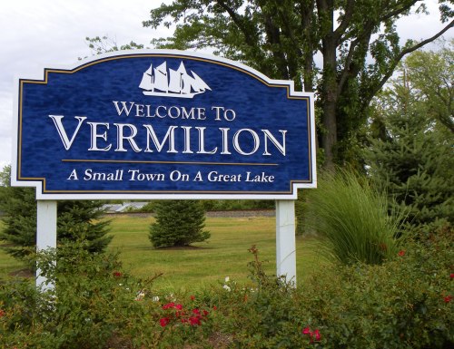 Sign welcoming visitors to Vermilion, featuring a blue background, white text, and decorative sailboat imagery.