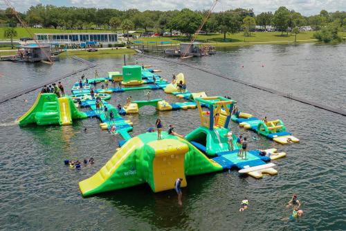 A colorful inflatable water park with slides and obstacles, filled with people enjoying the water on a sunny day.