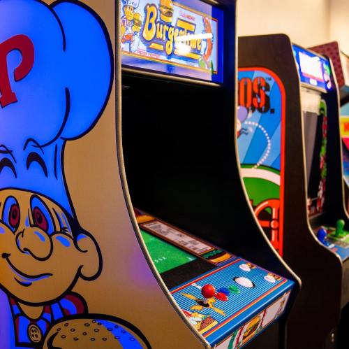A colorful arcade game cabinet featuring a cartoon chef with a burger, part of a retro gaming setup.