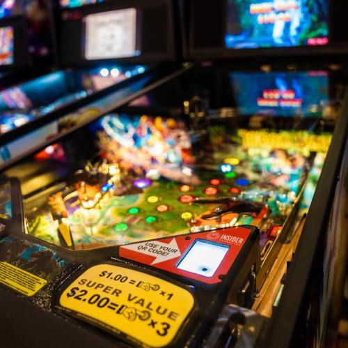 A close-up of a colorful pinball machine with illuminated playfield and a digital display.
