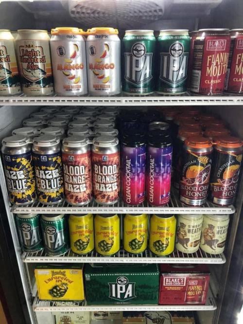 A refrigerator filled with various cans of craft beers and ales, showcasing different flavors and brands.