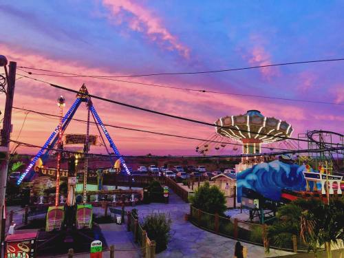 A vibrant sunset over a carnival with colorful rides and lights, creating a festive atmosphere.