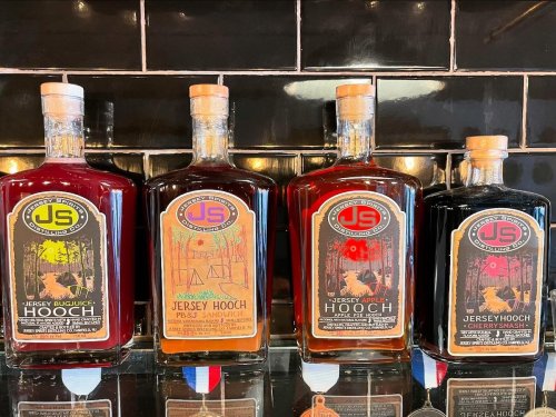 Four bottles of flavored hooch with colorful labels, displayed against a black tiled background.