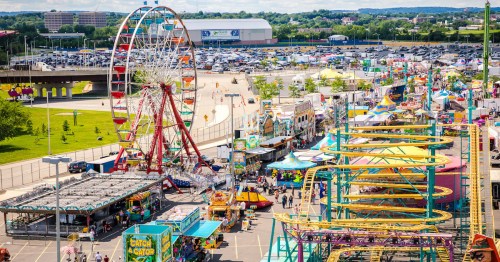 A vibrant amusement park scene featuring rides, games, and a Ferris wheel, bustling with visitors on a sunny day.