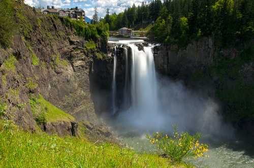 A scenic waterfall cascades down rocky cliffs, surrounded by lush greenery and a clear blue sky.