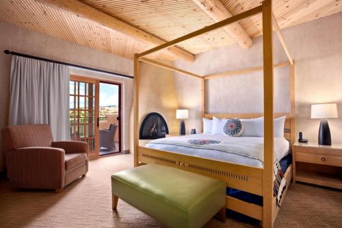 Cozy bedroom with a four-poster bed, armchair, and balcony access, featuring warm wood accents and soft lighting.