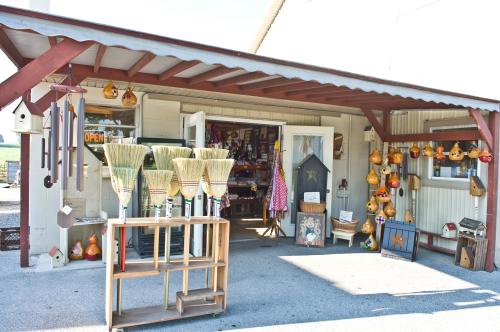 A quaint shop with brooms displayed outside, colorful decorations hanging, and an open sign visible.