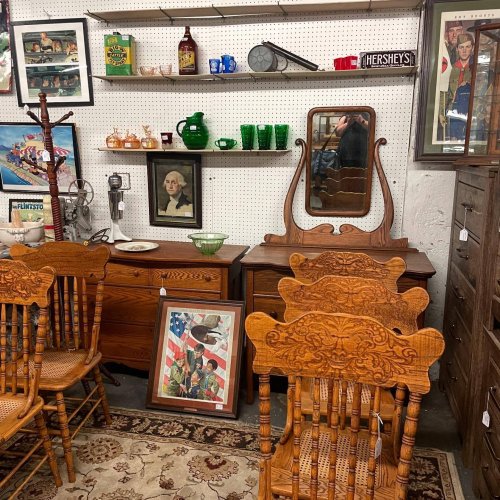 A vintage shop interior featuring wooden furniture, decorative items, and framed art on display.