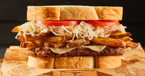 A hearty sandwich with a beef patty, melted cheese, fries, tomatoes, and shredded lettuce between two slices of bread.