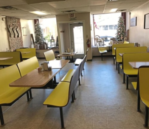 A cozy diner interior with yellow booths, tables, and holiday decorations, featuring a welcoming atmosphere.