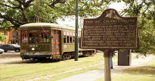 A vintage streetcar on the St. Charles Line, with a historical sign detailing its service since 1835.