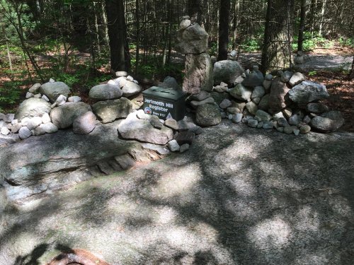 A stone arrangement at Jerimoth Hill, surrounded by trees and dappled sunlight on a rocky surface.