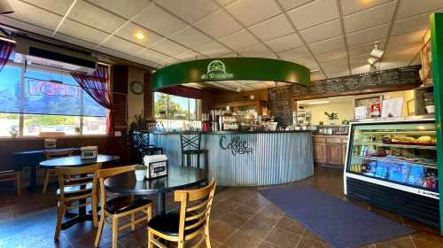 Cozy coffee shop interior with a circular counter, tables, and a display case, featuring warm lighting and inviting decor.