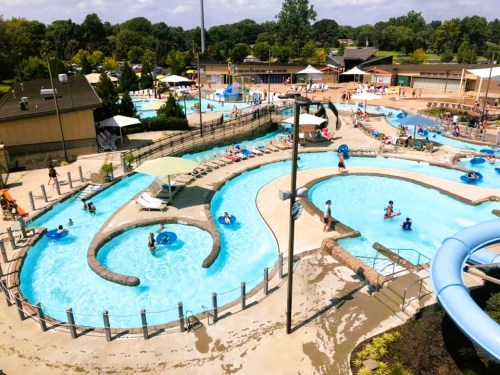 Aerial view of a water park featuring lazy rivers, slides, and people enjoying the sun and water activities.