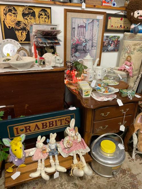 A vintage shop display featuring rabbit dolls, decorative items, and a wooden sign reading "I-RABBITS."