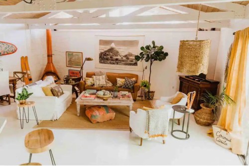 Bright, cozy living room with a mix of modern and rustic decor, featuring a sofa, coffee table, plants, and warm lighting.