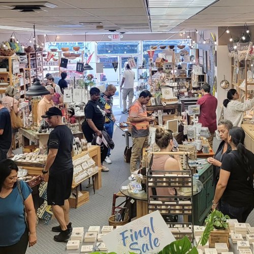 A busy store filled with shoppers browsing various products, with shelves and displays throughout the space.