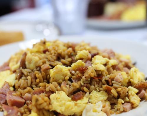 A close-up of a plate filled with fried rice, scrambled eggs, and diced ham.