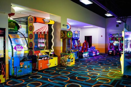 Brightly lit arcade with various colorful games and machines in a spacious room.
