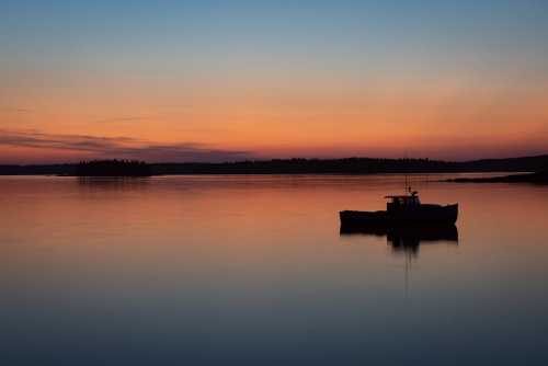 A tranquil sunset over calm waters, with a lone boat silhouetted against the colorful sky.