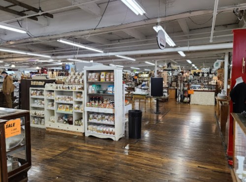 Interior of a spacious market with wooden floors, shelves of products, and various displays throughout the area.