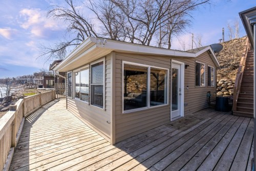 A cozy lakeside cabin with large windows, surrounded by trees and a wooden deck, overlooking the water.