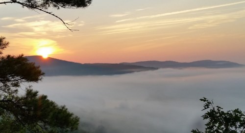 A serene sunrise over misty mountains, with soft clouds blanketing the valley below.