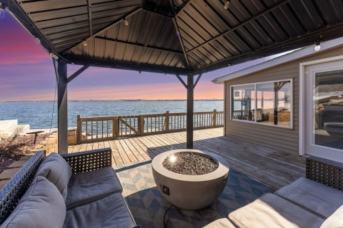 Cozy outdoor seating area with a fire pit, overlooking a serene waterfront at sunset.