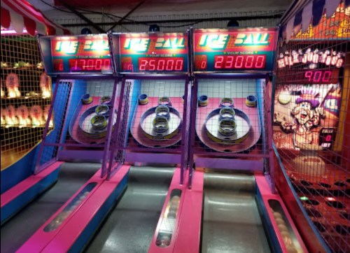 Three colorful arcade games with scoreboards displaying points, featuring a vibrant carnival theme.