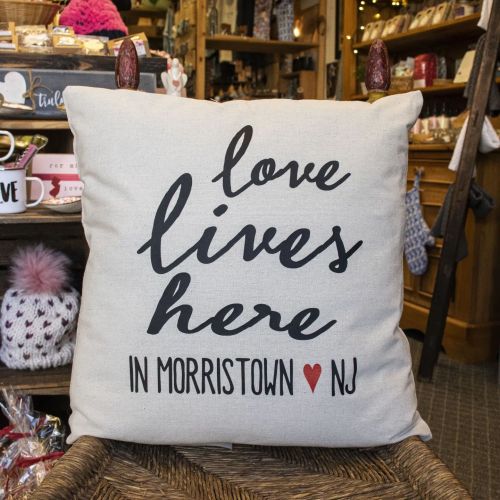 A decorative pillow with the text "love lives here in Morristown NJ" on a neutral background.