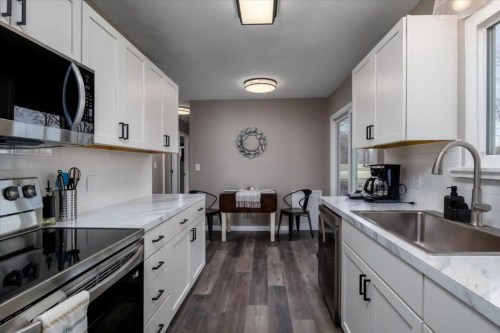 Modern kitchen with white cabinets, stainless steel appliances, and a dining area featuring a round table and chairs.