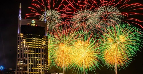 Colorful fireworks burst over a city skyline featuring the AT&T building, illuminating the night sky.