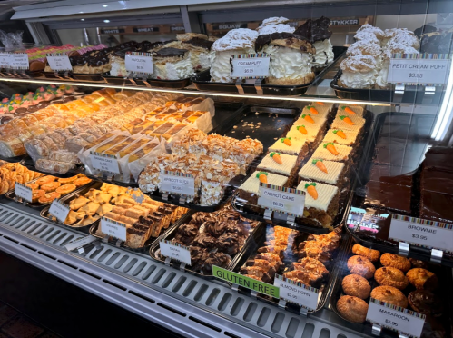 A display case filled with various pastries, cakes, and desserts, including carrot cake and gluten-free options.