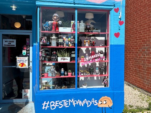 Colorful storefront featuring a display of toys and drinks, with a sign promoting "Best Empanadas" and playful graphics.