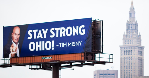 Billboard featuring the message "STAY STRONG OHIO!" by Tim Misny, with a city skyline in the background.