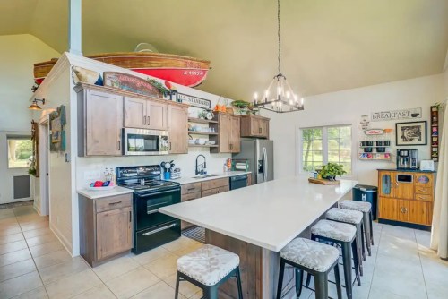 Bright kitchen with wooden cabinets, a large island, and a boat decor above. Features modern appliances and a cozy atmosphere.