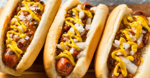 Three Coney Island hot dogs with beef sauce, onion, and mustard in a row