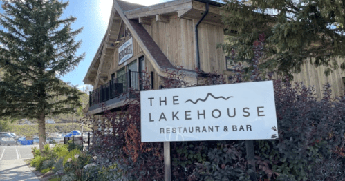 A wooden building with a sign reading "The Lakehouse Restaurant & Bar" surrounded by trees and shrubs.