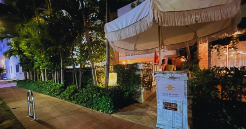 A cozy outdoor entrance to a restaurant, surrounded by greenery and softly lit at night.